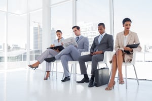 Well dressed business people sat together in a waiting room