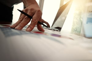 business documents on office table with smart phone and laptop computer and graph business with social network diagram and man working in the background