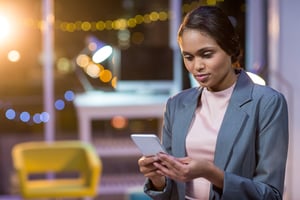 Businesswoman text messaging on mobile phone in office at night